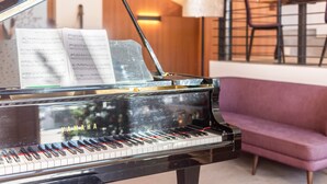 Ein Flügel mit Notenblättern, ein violettes Sofa und ein Essbereich mit Stühlen und einem Tisch.
