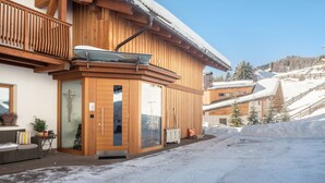 Eine Holzchalet mit Balkon, Schiebeglastür und schneebedecktem Dach.