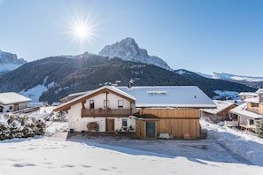 Un bâtiment de style chalet, avec une façade en bois, un balcon et un toit recouvert de neige.