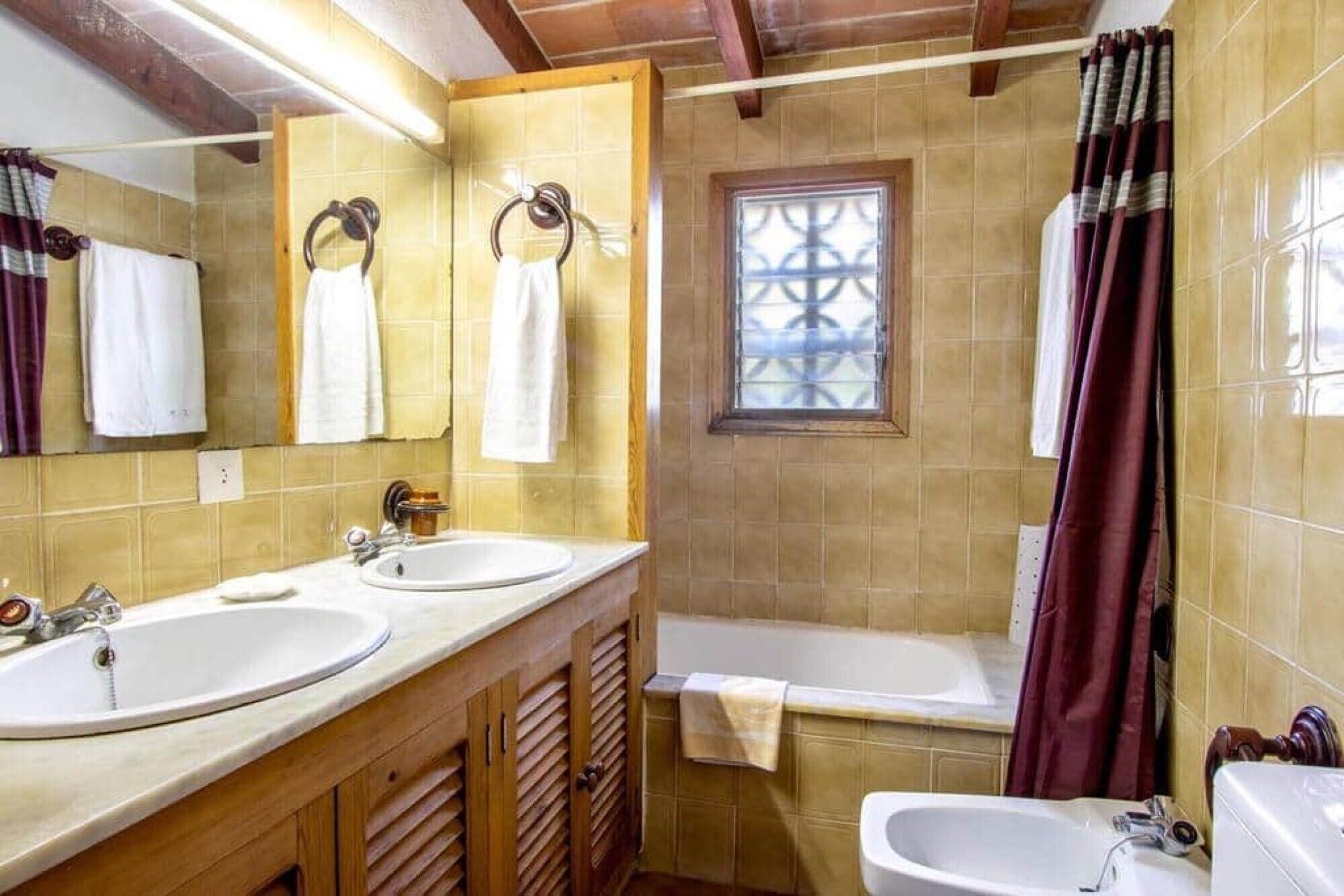 A bathroom with two sinks, a bathtub, and a window.