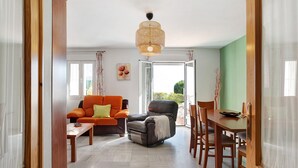 Een woonkamer met een bank, fauteuil, eettafel en stoelen.