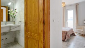 Een badkamer met een houten deur, een wastafel en een spiegel.