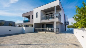 A modern multi-story building with a flat roof terrace, balconies, and a paved courtyard. - Apartment Spanic 2 (Vir)