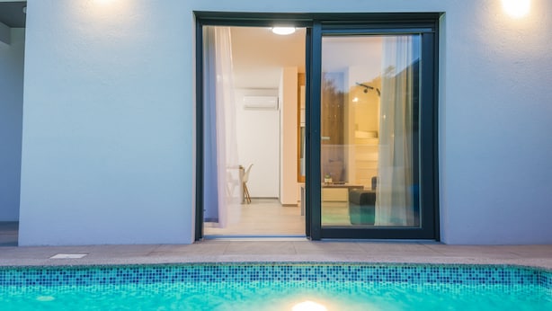 A modern house with a swimming pool, a glass door leading to a kitchen, and a visible staircase. - Apartment Spanic 2 (Vir)