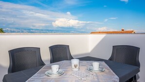 A table set with white cups and saucers, a heart-shaped mug, and a napkin on a balcony with a clear view of the sky and distant mountains. - Apartment Spanic 2 (Vir)