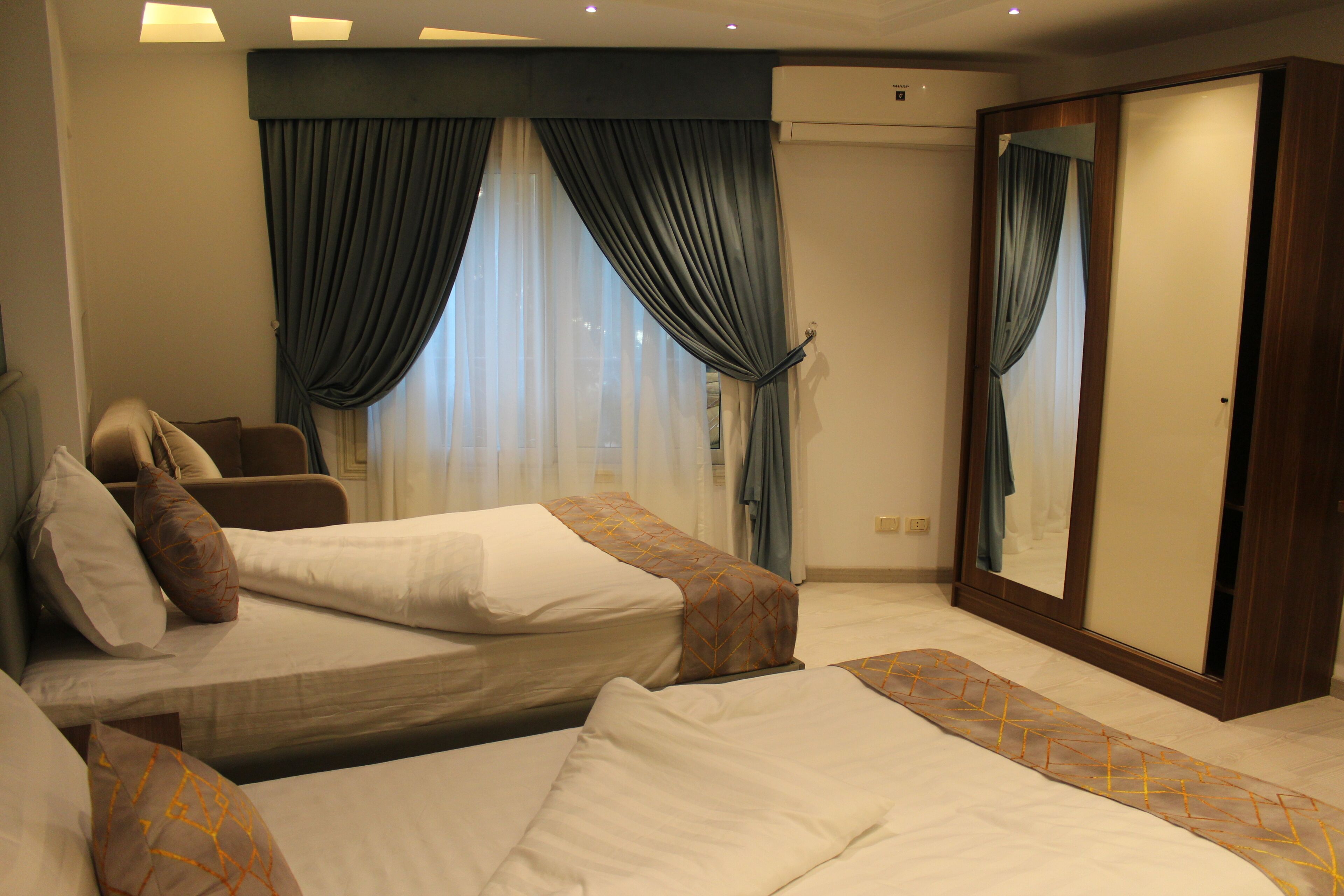A hotel room with two beds, a large mirror, and a wardrobe.