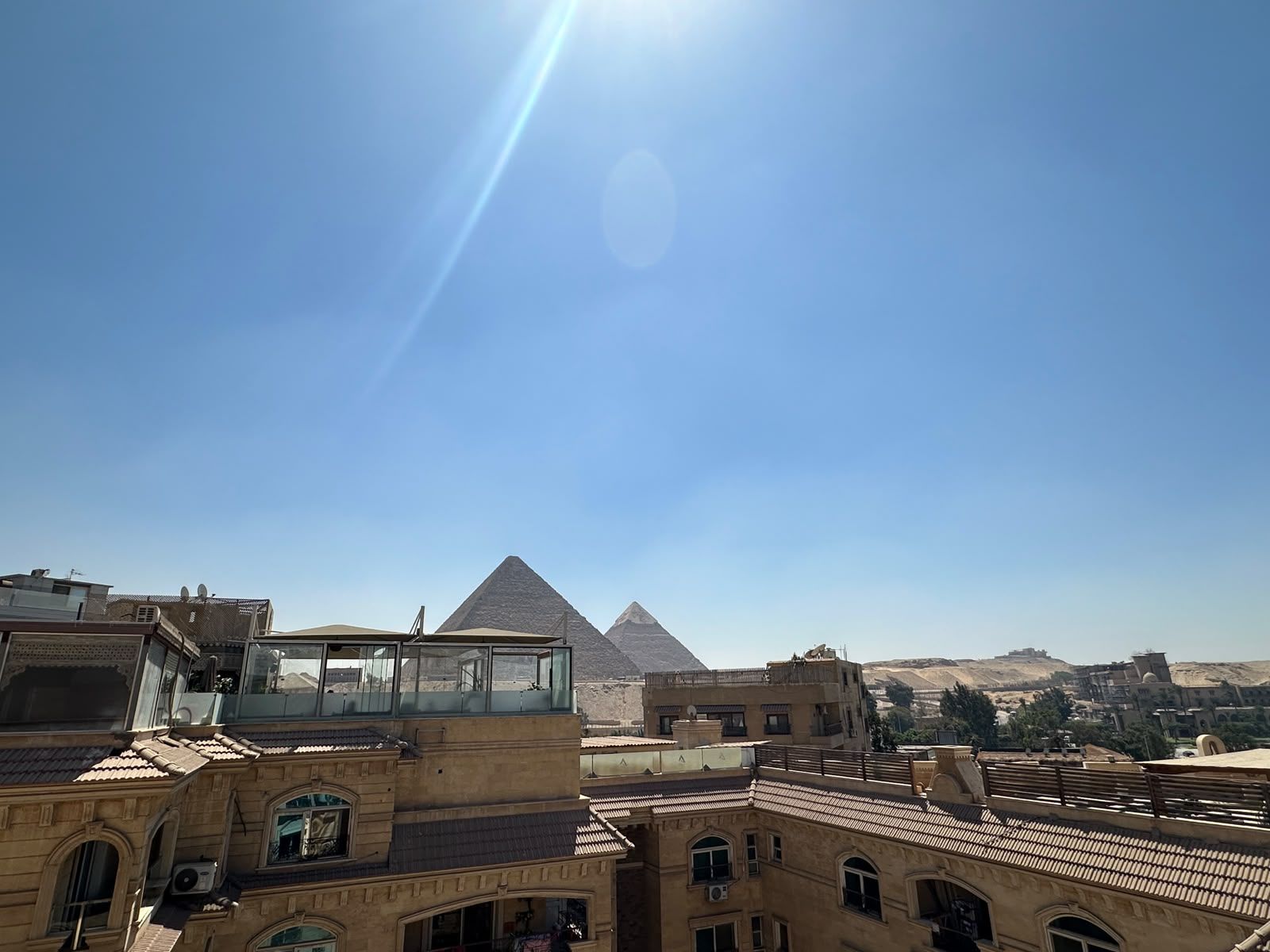 A building with a glass viewing platform overlooking a pyramid.