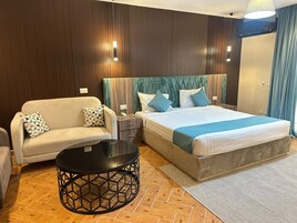 A hotel room with a bed, a sofa, a nightstand, and a round table.