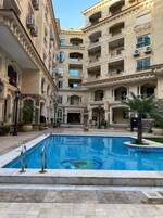 Un patio con piscina rodeado de edificios de varios pisos con balcones y unidades de aire acondicionado.