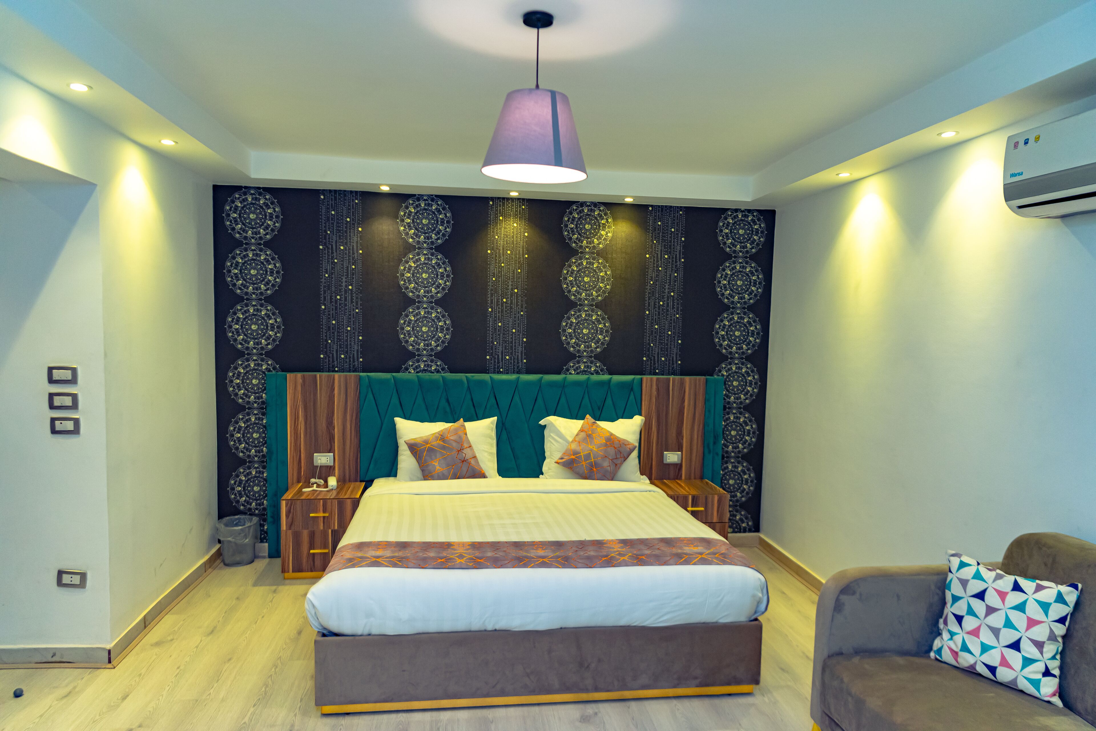 A modern bedroom with a large bed, a headboard with a decorative pattern, a bedside table, and a nightstand.