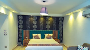 A modern bedroom with a large bed, a headboard with a decorative pattern, a bedside table, and a nightstand.