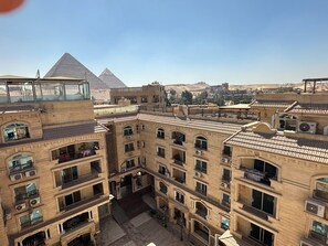 A multi-story building with balconies and a view of the pyramids in the background. - Jasmine Pyramids Hotel (Giza)