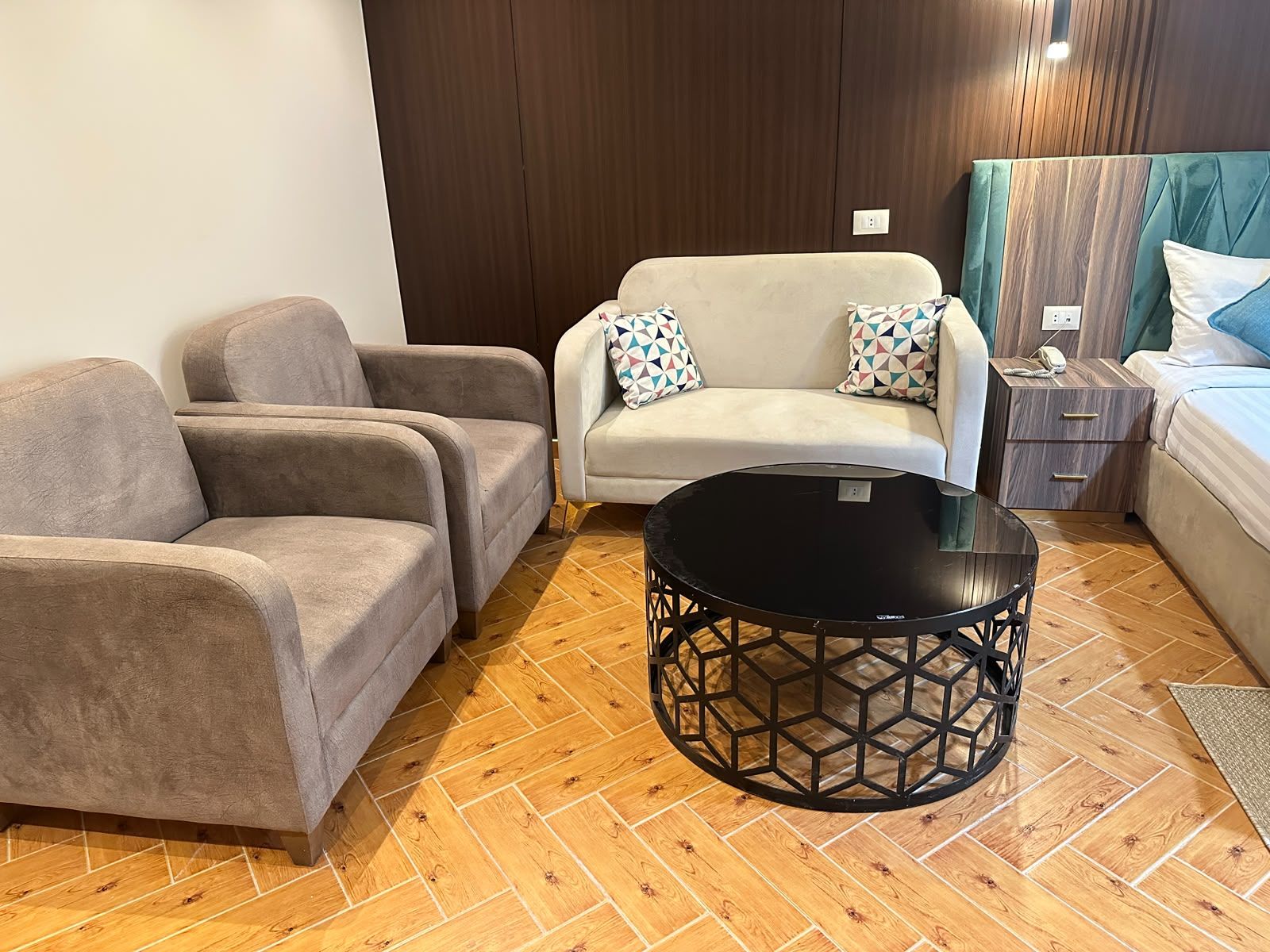 Una sala moderna con un conjunto de sofá, una mesa de centro y una mesita de noche con un teléfono.