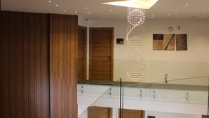 Un interior moderno con paneles de madera, barandilla de cristal y una lámpara de diseño único.