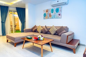 Una sala de estar moderna con un sofá modular, una mesa de centro de madera y un amplio ventanal con cortinas.
