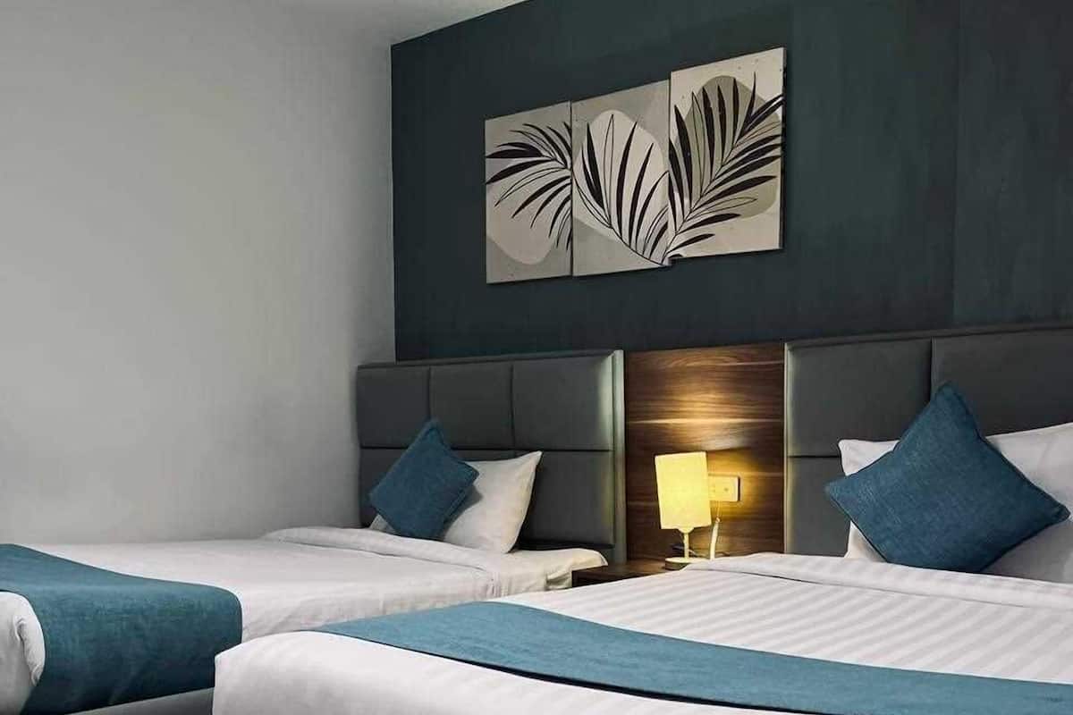 Habitación de hotel moderna con dos camas, una obra de arte grande encima de ellas y una mesita de noche con una lámpara.