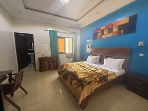 A bedroom with a bed, a wooden nightstand, a desk, and a chair. - Ideal studio for couples (DAKAR)