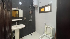Un bany amb un lavabo blanc, un vàter i una dutxera.