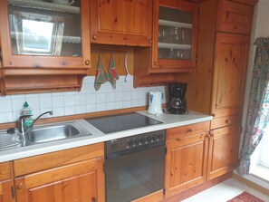 Una cocina con armarios de madera, un lavamanos doble, una cafetera y un lavavajillas.