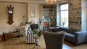 Ein gemütliches Wohnzimmer mit Kamin, Bücherregal, einer Uhr und einer Chandelier.