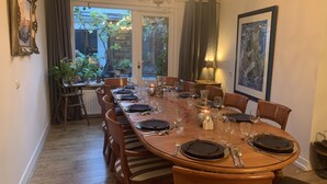 Ein Essbereich mit einem langen Holztisch, gedeckt für eine Mahlzeit, umgeben von Holzstühlen.