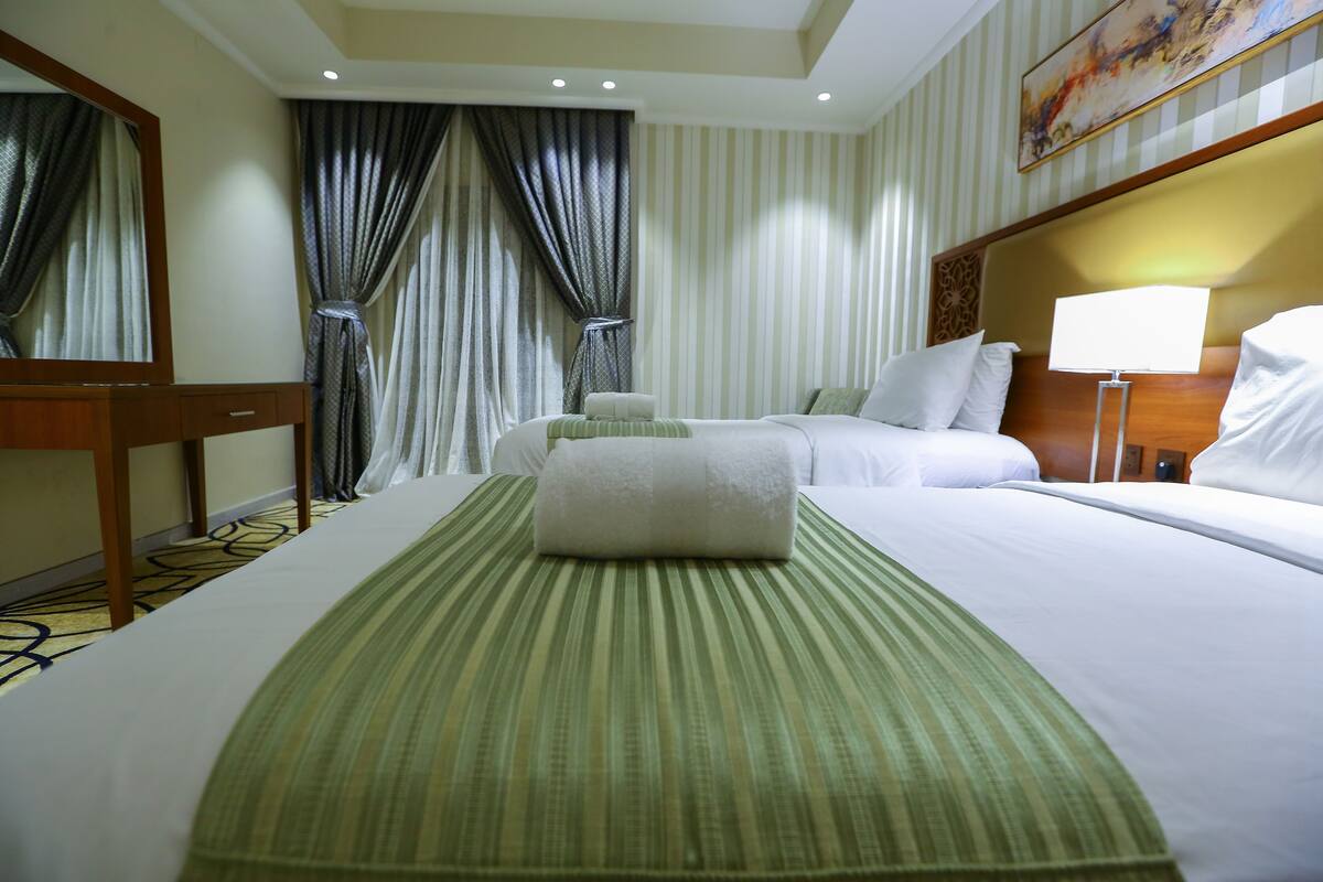 A hotel room with a large bed, a bedside table, a lamp, and a painting on the wall.