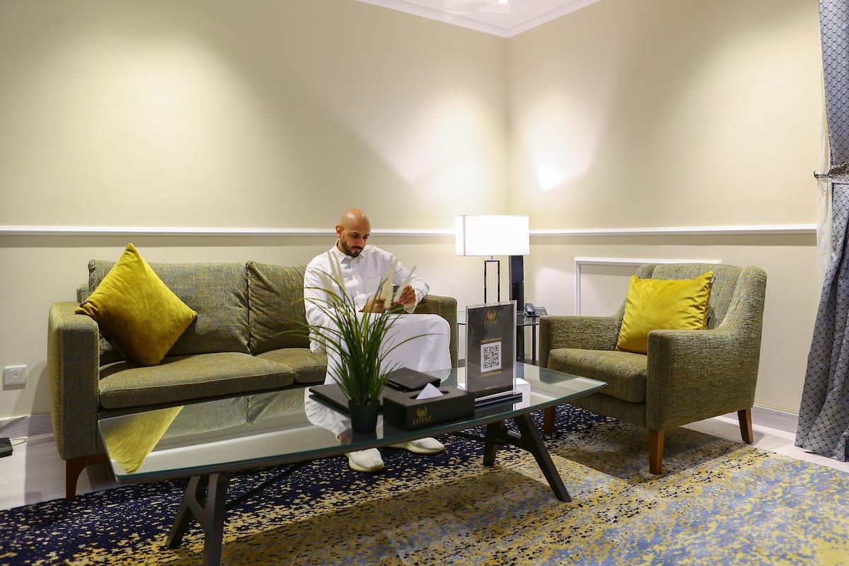 A room with two sofas, a glass coffee table, a lamp, and a QR code stand.