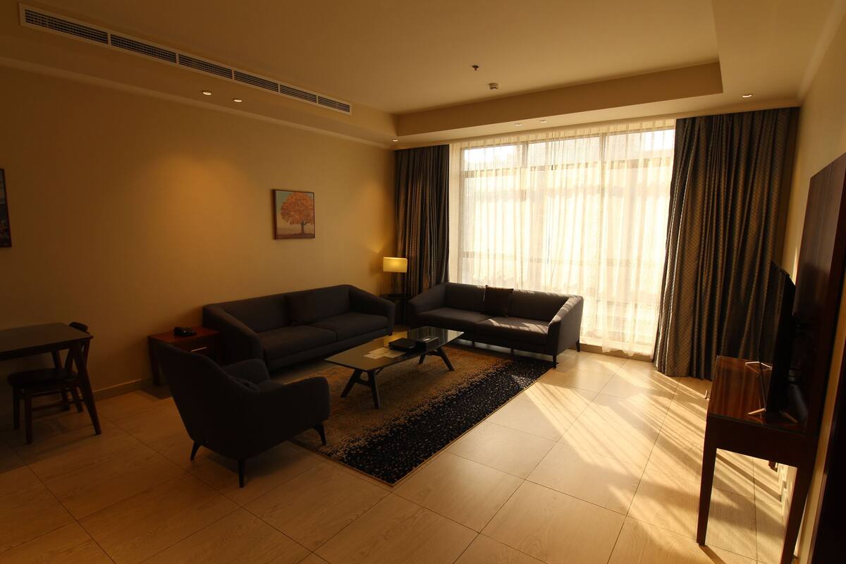 A modern living room with a sofa, armchairs, a coffee table, and a TV.