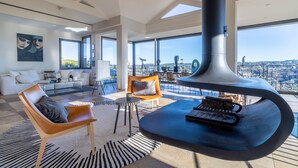 Un amplio salón con un gran ventanal, una chimenea moderna y muebles contemporáneos.