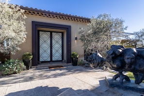 A building with a tiled roof, a decorative entrance with a glass door, and two stone sculptures.