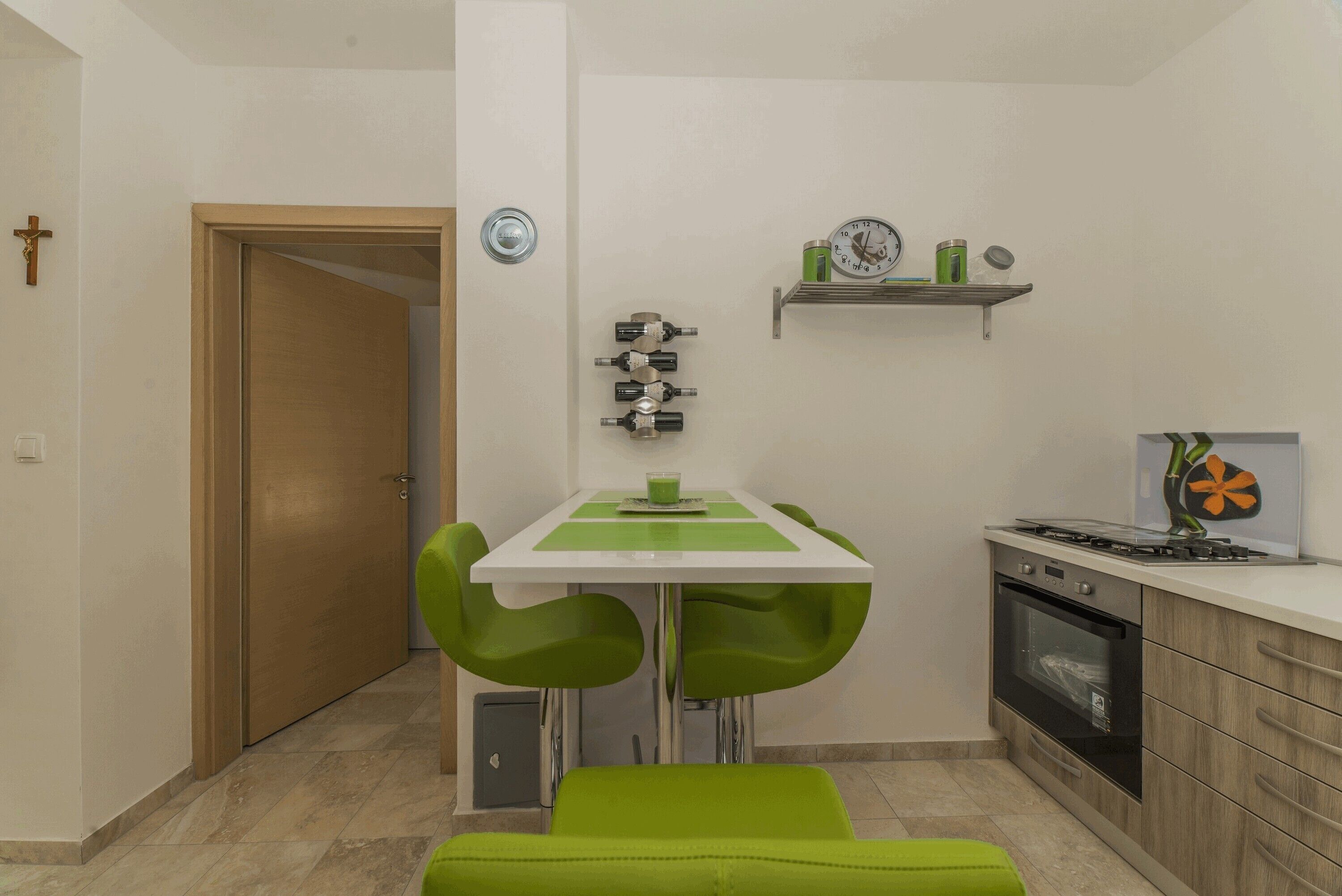 A compact kitchen with a dining table, two chairs, a small oven, and a sink.