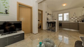 A modern living room with a flat-screen TV, a sofa, and a decorative bowl on a glass table. - Apartment Stichling (Vir)