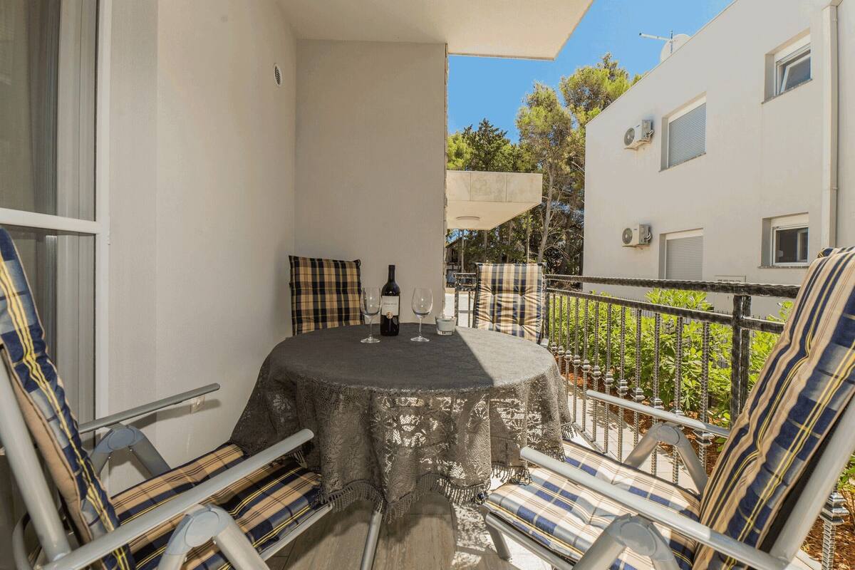 Un balcon avec une table dressée pour deux personnes, agrémenté de chaises à carreaux et d’une nappe.