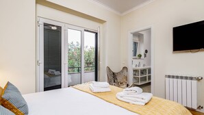 Ein Hotelzimmer mit Bett, Bad, Fernseher und einem Balkon mit Blumen.