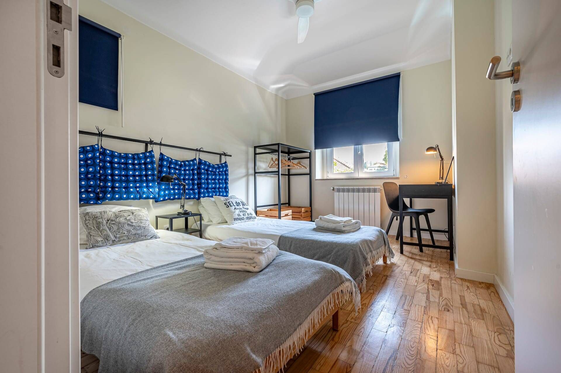 A bedroom with two beds, a desk, and a chair.