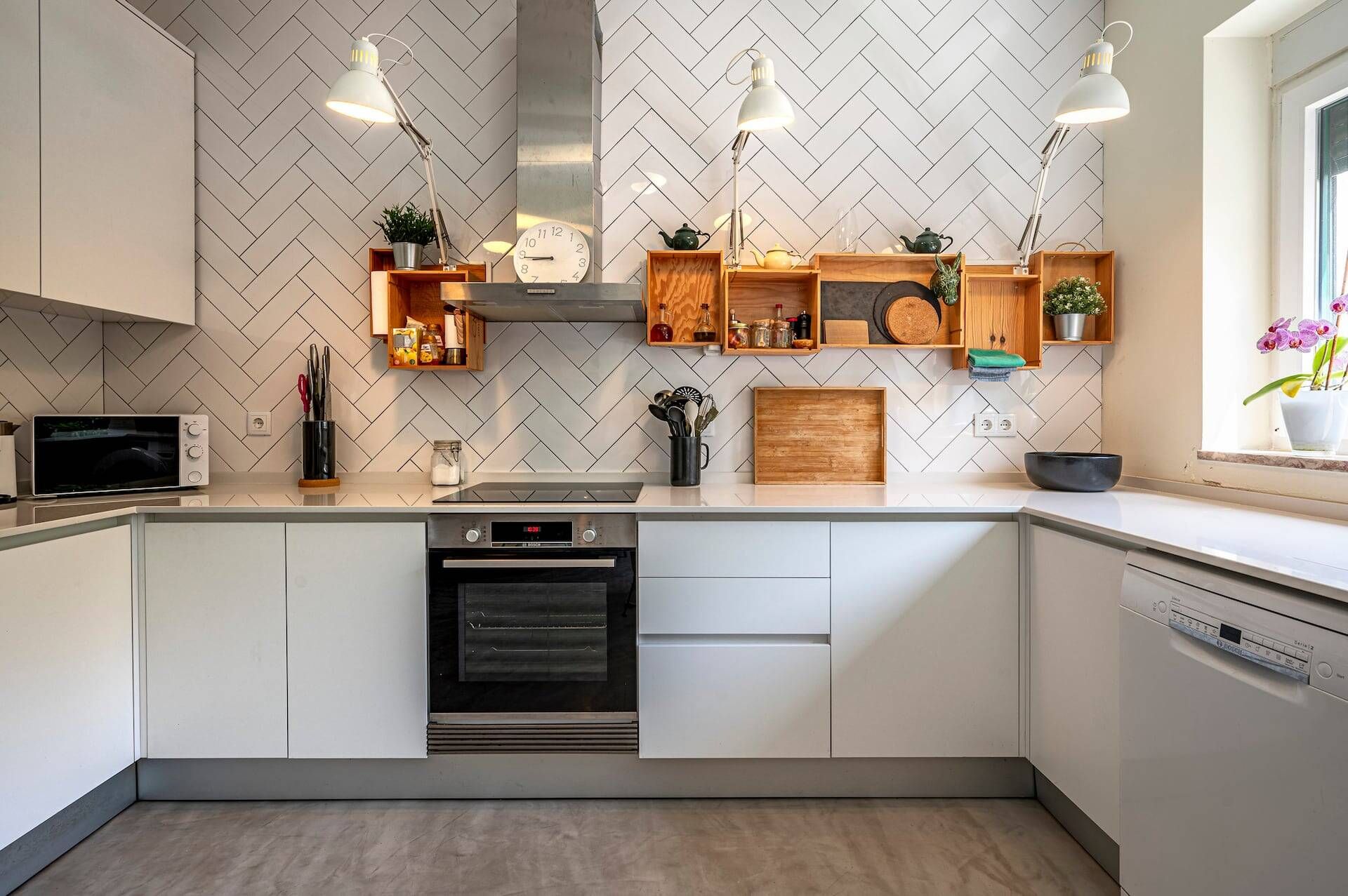 A modern kitchen with white cabinetry, a microwave, an oven, and pendant lights.