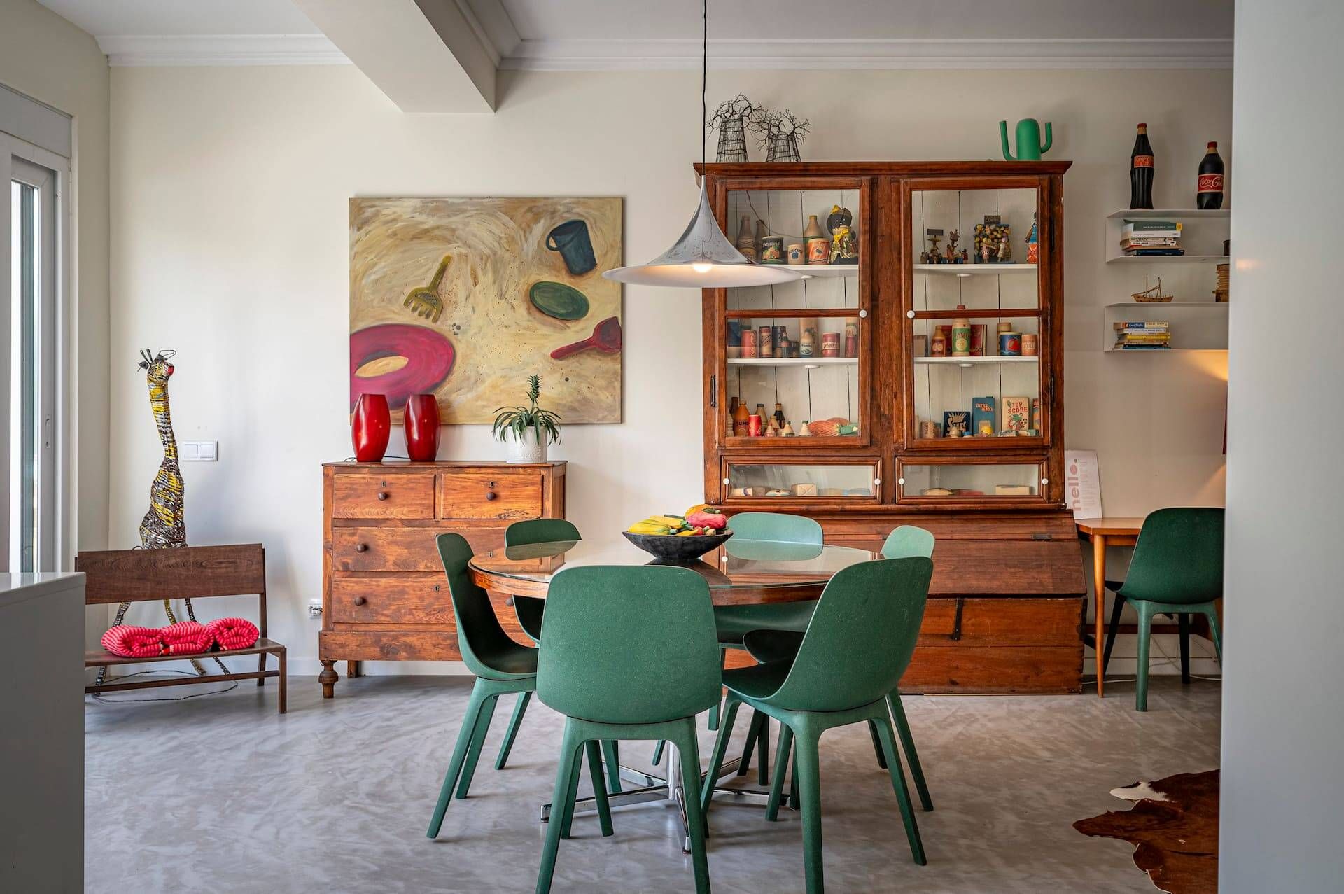 A dining area with a wooden cabinet, green chairs, and a table.