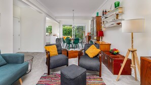 Ein modernes Wohnzimmer mit einer Couch, Sesseln, einem Couchtisch und einem Essbereich mit Stühlen und einem Tisch.