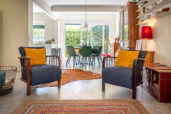 A modern living room with two armchairs, a dining area, and a view of the outdoors.