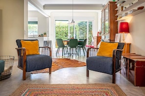 Een moderne woonkamer met twee fauteuils, een eethoek en uitzicht op het omliggende landschap.