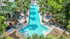 A rectangular swimming pool surrounded by palm trees and lounge chairs, with a small boat docked at one end. - Renovated Seagrove Home with LSV & Pool Access (Santa Rosa Beach)