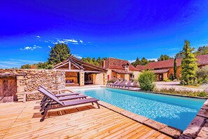 A wooden deck with lounge chairs and a swimming pool.