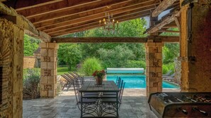 Une terrasse extérieure avec une table et des chaises, une piscine et un espace barbecue.