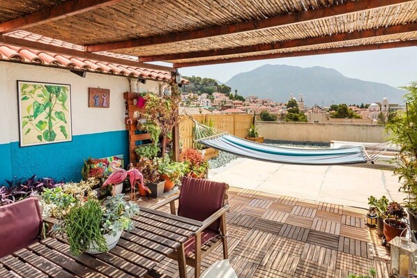 Un patio cubierto con una hamaca, muebles de madera y plantas en macetas.