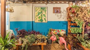 Eine Terrasse mit verschiedenen Kübelpflanzen, einer Holzbank und einer Flamingofigur.