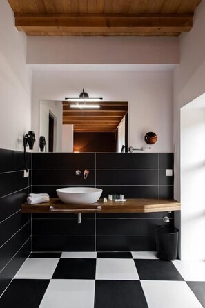 A modern bathroom with a black and white checkered floor, a wooden vanity, a white sink, and a mirror above the sink. - Hotel Posta Mestia (Mestia)