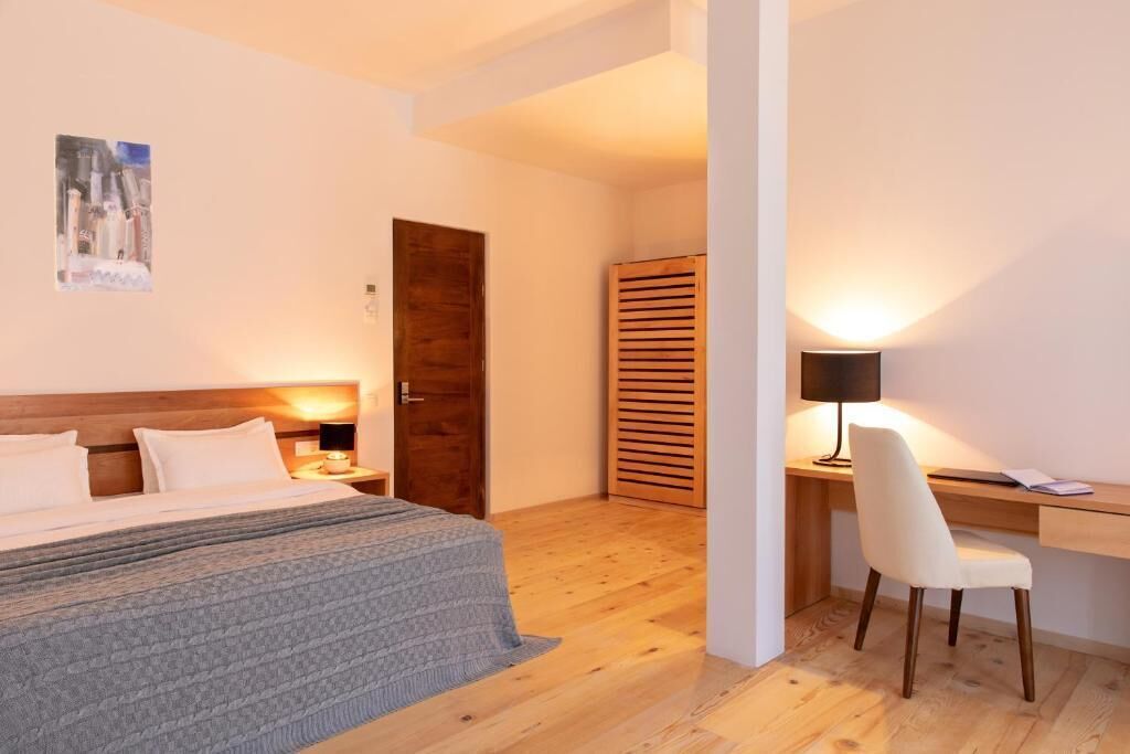 A bedroom with a wooden bed, a desk with a chair, and a wardrobe.