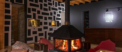 A cozy room with a wood-burning stove, patterned wall, and a sign for 'POSTA HOTEL'.