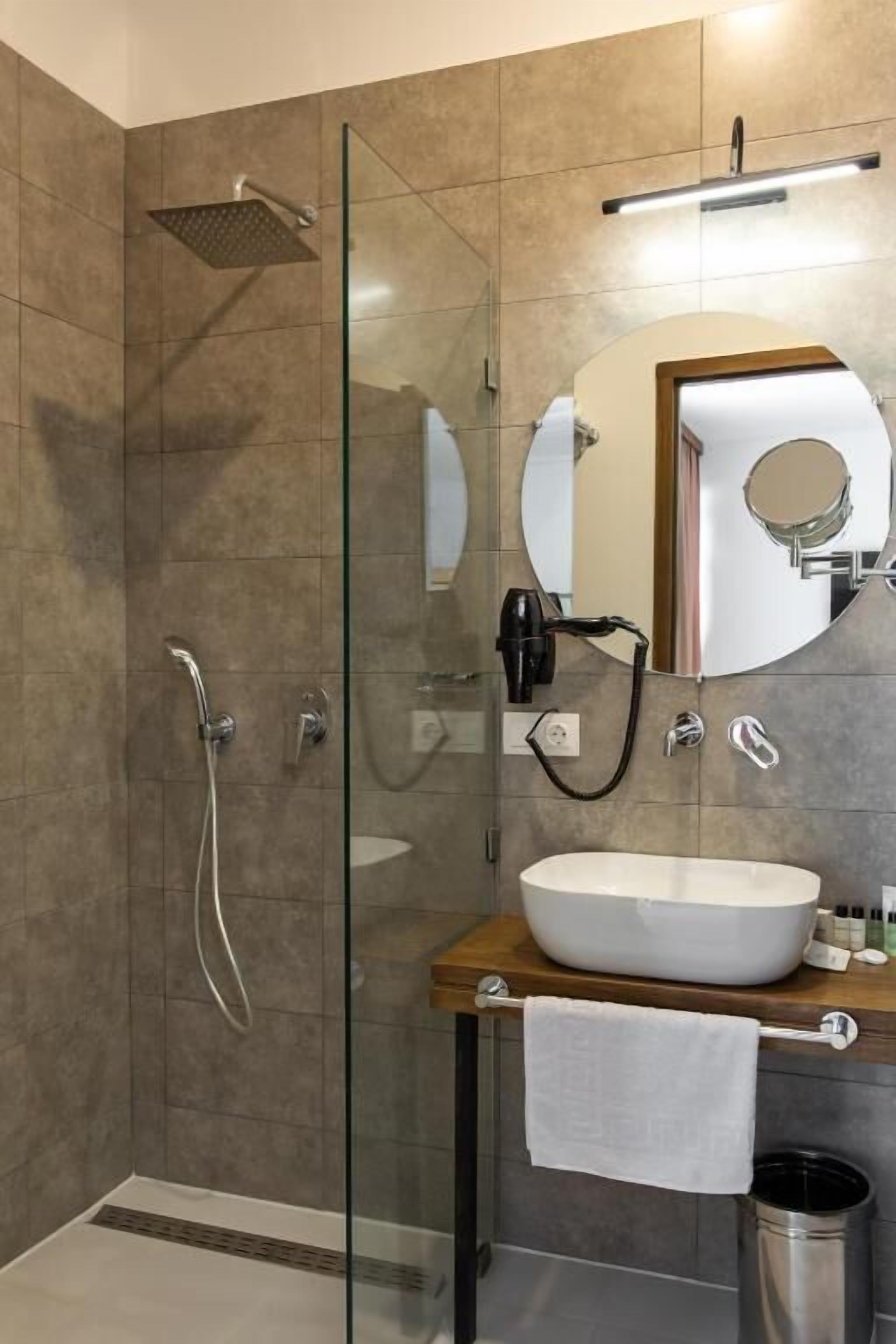 Ein modernes Badezimmer mit einer Duschkabine aus Glas, einem großen Spiegel und einem weißen Waschbecken.