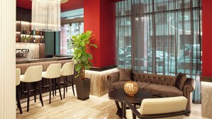 A modern living area with a sofa, a coffee table, and a bar area with stools and a potted plant. - Zeus Essence Athens Central, Trademark Collection by Wyndham (Athens)